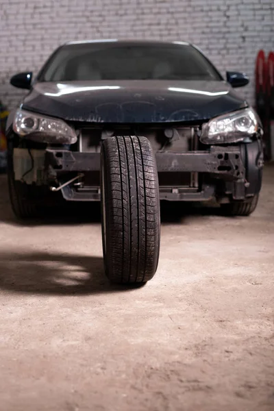 Foto av ett bildäck på bakgrunden av en personbil utan stötfångare — Stockfoto