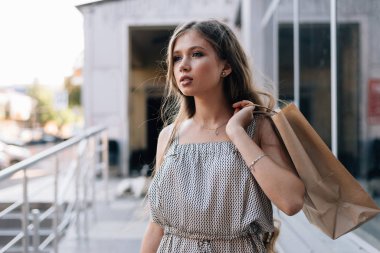 Alışveriş merkezinin önünde elinde kese kağıdıyla genç bir kızın yakın çekimi.