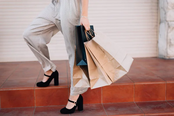 En tjej i byxor efter shopping står på trappan med packa — Stockfoto