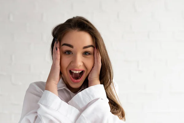 The girl holds her hands behind her head and screams in a cheerful tantrum, close-up on a white background — Stock Photo, Image