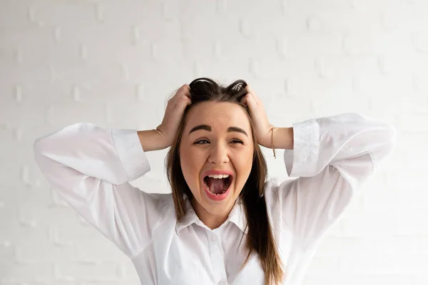 The girl in hysterics and confusion clutched her hands at her head, a white background — Stock Photo, Image