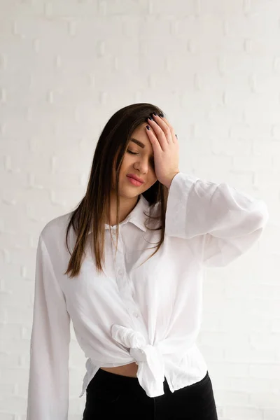 En ung flicka i vit skjorta och svarta byxor håller handen över huvudet, besviken — Stockfoto