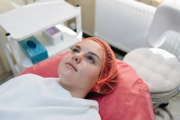 Молодая женщина лежит на диване в косметическом кабинете и готовится к процедуре очищения лица — стоковое фото