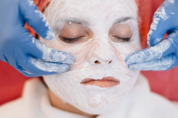 Primer plano de la mujer que se somete a un procedimiento cosmético en la cara, las manos de un médico con guantes — Foto de Stock