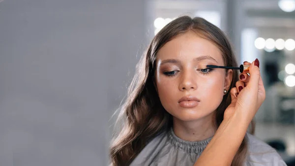 Tvář mladé ženy, která je natřená řasami v salónu krásy, večerní make-up před akcí — Stock fotografie