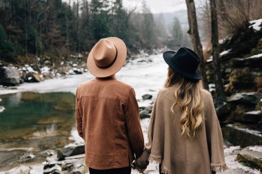 young couple in love walks through the woods near the river. Travelers and adventurers, camping, traveling after the wedding.