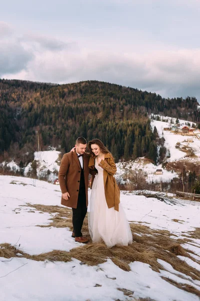 Un elegante par de amantes se paran sobre un fondo de montañas cubiertas de nieve . — Foto de Stock