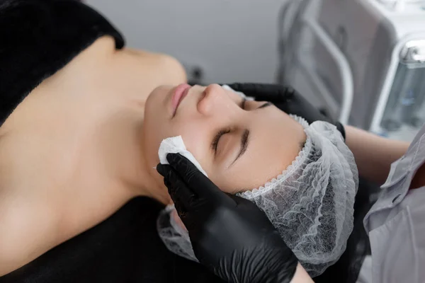 Beautician wipes a woman\'s face with wet wipes. peeling facial skin cleansing.