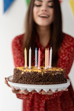 Genç ve şık bir kız elinde bir pasta tutuyor. Bayram doğum günü. Arkadaşlar için parti. Pastadaki mumlar ve mesajın için yer..