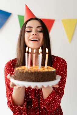 Genç güzel kız pastadaki mumları üflüyor. Tatilin şerefine harika bir parti..