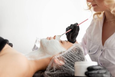 Bir kız resepsiyonda kanepede uzanır ve yüzüne maske takılır. Soyuluyor. Gözenek temizliği. Deriyi nemlendirir ve benekleri parlatır..