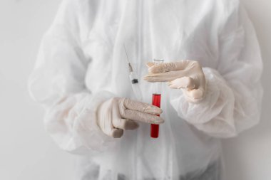Elinde şırınga ve deney tüpü olan koruyucu kıyafetli bir doktor ya da laboratuvar asistanı. Coronavirus tedavisi konsepti. Tüm dünya için bir aşı arayın..