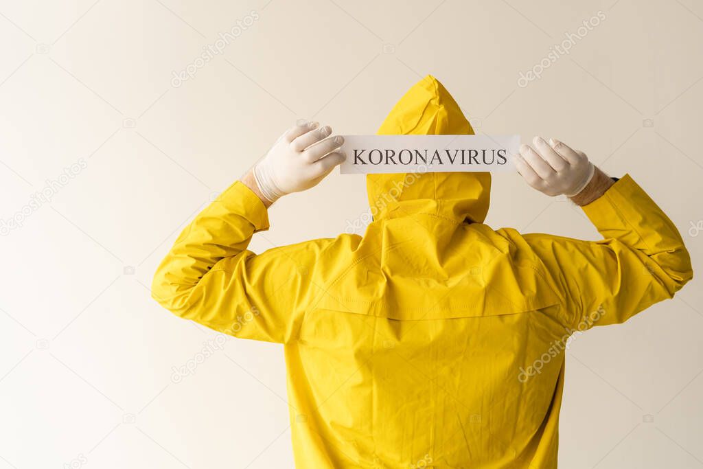 The new coronavirus is the 2019 nKoV virus concept, a man infected with the virus is dressed in a protective suit and holds a tablet with the name of the disease. Place for text. unknown patient.