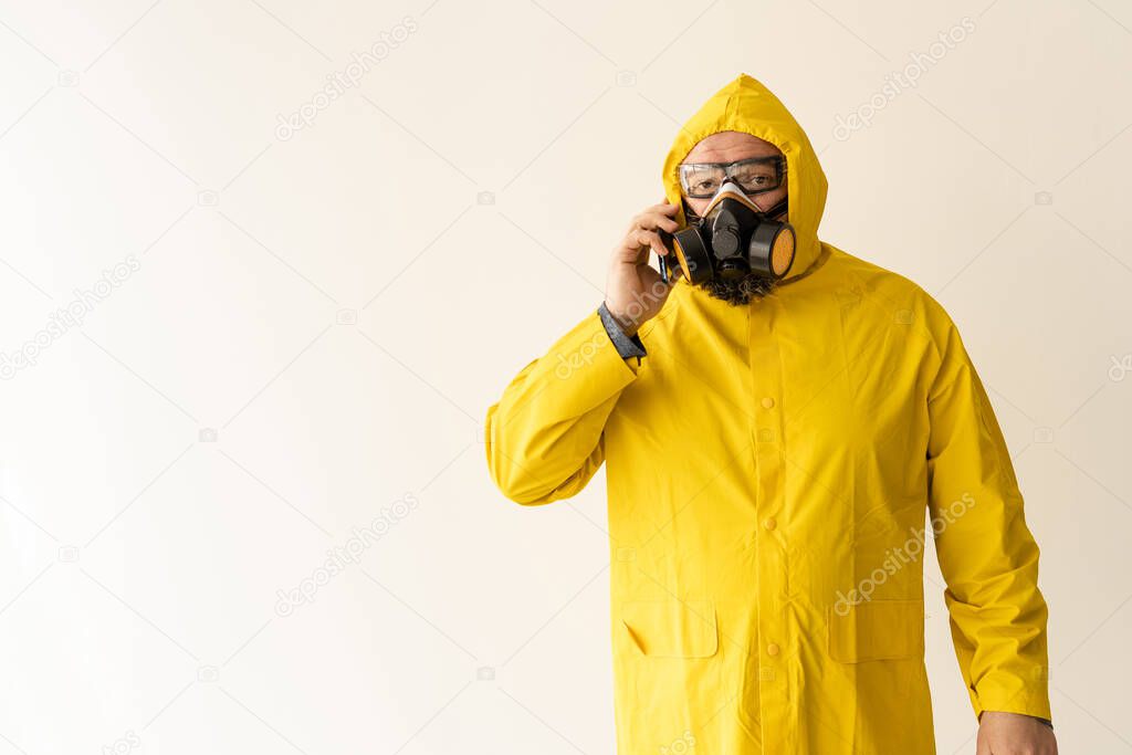 a man dressed in a yellow protective suit communicates on a cell phone. The concept of quarantine protection from the whole world
