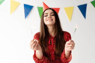 Doğum günü tatili, genç, güzel ve şık bir kız elinde iki maytap tutuyor. Şapka kafaya giydirilmiş. Parti başlıyor.