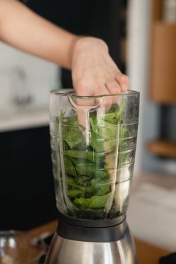 Sağlıklı yeşil sebzelerle karıştırıcıyı kapat. Lezzetli ve sağlıklı bir kahvaltı. Kadın eli, ıspanağı helikoptere boşaltıyor.