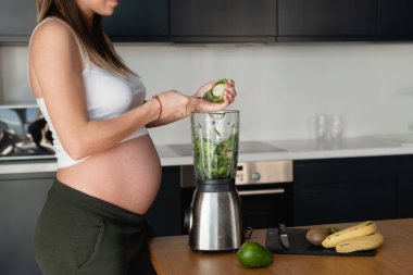 Çocuk için sağlıklı bir kahvaltı. Genç bir kadın bebek bekliyor. Koca bir hamile göbeği. Sağlıklı yaşam tarzı ve doğal vitamin kavramı.