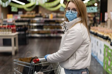 Alışveriş merkezinde yürürken yüzüne hijyenik koruyucu maske takan Avrupalı bir kadın. Sağlık ve hastalık önleme Coronavirüs, Covid19 kalabalık bir yerde grip.