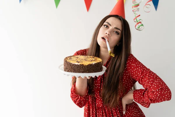 一个有着白色背景的蛋糕的可悲的女孩 一个无聊的庆祝活动和一个糟糕的派对 假期准备不足 — 图库照片
