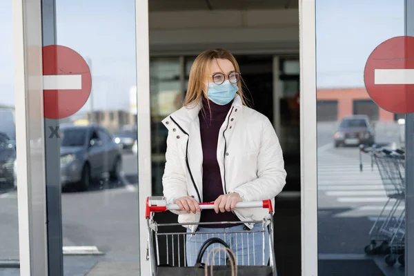 Yüzünde tıbbi maske olan genç ve güzel bir kadın süpermarketin kapısından çıkıp önüne bir tramvay itiyor. Karantina sırasında panik. Halka açık bir yerde virüs koruması.