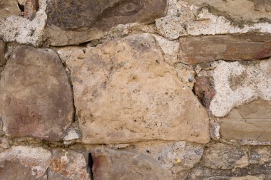 Çimento katmanları arasında uzanan farklı boyutlarda taşlardan oluşan bir duvarın dokusu.