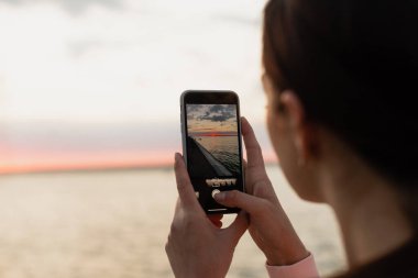 Genç bir kız, bir atlet, bisiklet sürdükten sonra, denize geldi, şafağın fotoğraflarını çekti, denize baktı ve spor yapmaktan dinlendi..