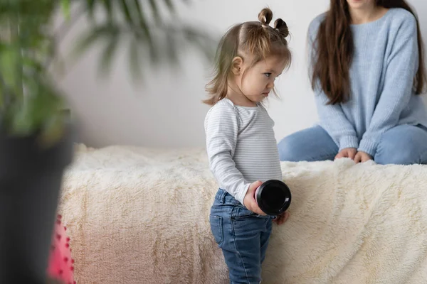 Beleidigtes kleines Mädchen schmollt, steht neben dem Bett. Beziehung Eltern und Kinder. — Stockfoto