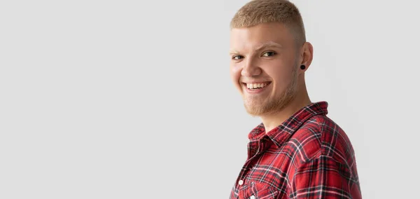 Gelukkig glimlachen blond man op een licht achtergrond gekleed in een rood shirt. — Stockfoto