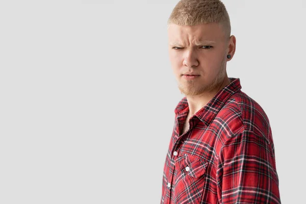 Jovem bonito loiro homem vestido com uma camisa vermelha com um olhar sério olha para a câmera . — Fotografia de Stock