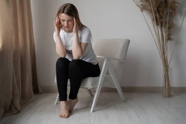 Sandalyede oturan depresyonlu bir kadın. Kötü ruh hali ve enerji azalması. Gün boyu baş ağrısı