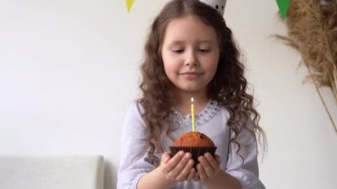 Doğum günü keki olan çocuk. Küçük kız doğum günü pastasına mum üflüyor. Mum kendini yaktı..