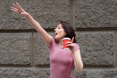 Sabahın erken saatlerinde genç ve güzel bir kadın sokakta taksiye biner. Elinde kahve olan kağıt bardak. Metin için yer