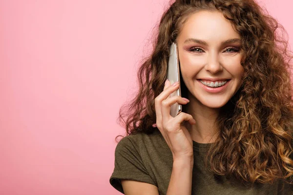 Mooi meisje met mobiele telefoon op roze achtergrond — Stockfoto