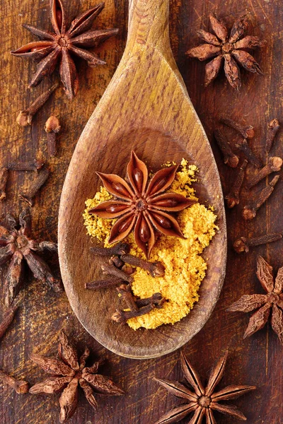 Star anise, curry and cloves on wooden spoon