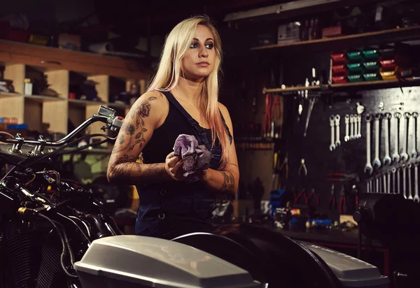 Mujer rubia mecánica en un taller de motocicletas — Foto de Stock