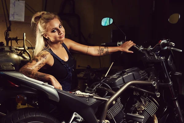 Mujer rubia mecánica en un taller de motocicletas — Foto de Stock