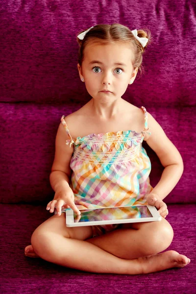 Mała, Ładna dziewczyna z komputera typu tablet na kanapie w domu — Zdjęcie stockowe