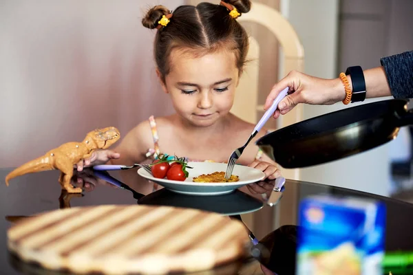 Mère met des crêpes de pommes de terre dans une assiette à une fille — Photo