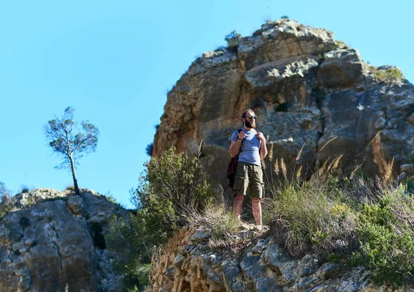 Bebaarde man reiziger staande op een rand van de berg — Stockfoto