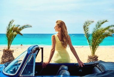 Tropik sahilde retro car yakınındaki çekici kadın 