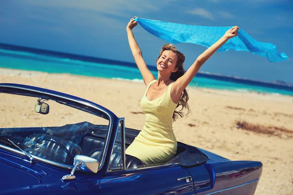 Happy woman with a hands raised sitting in retro cabriolet car — Stock Photo, Image