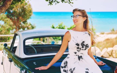 Güzel zarif kadın poz turkuaz denize karşı retro car yakınındaki