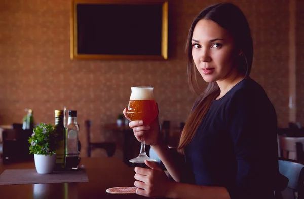 Joven morena bebiendo una cerveza en un restaurante — Foto de Stock