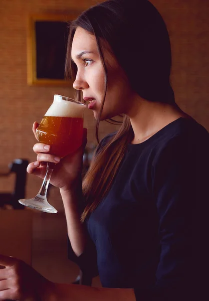 Молодая брюнетка пьет пиво в ресторане — стоковое фото