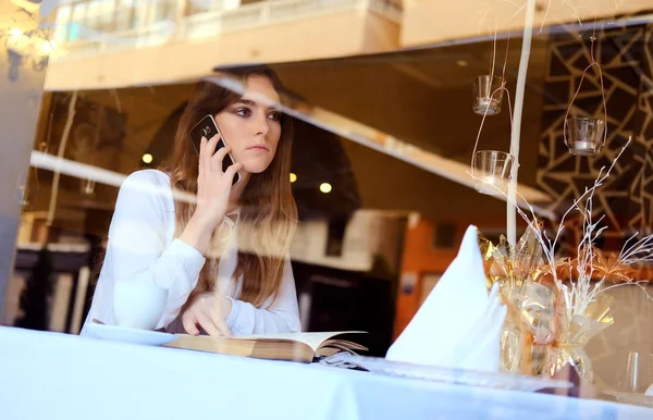 Młoda brunetka rozmawia przez telefon w restauracji — Zdjęcie stockowe