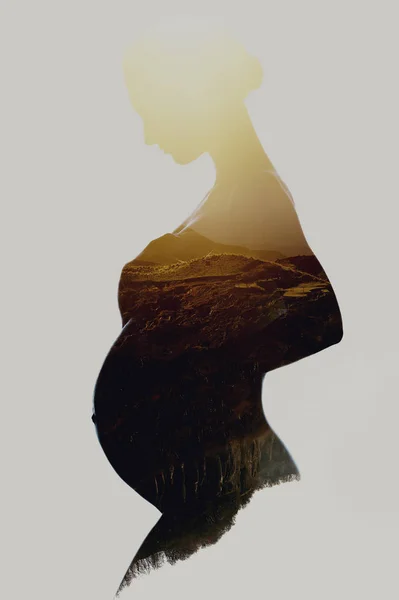 Beautiful silhouette of pregnant woman combined with a mountains — Stock Photo, Image