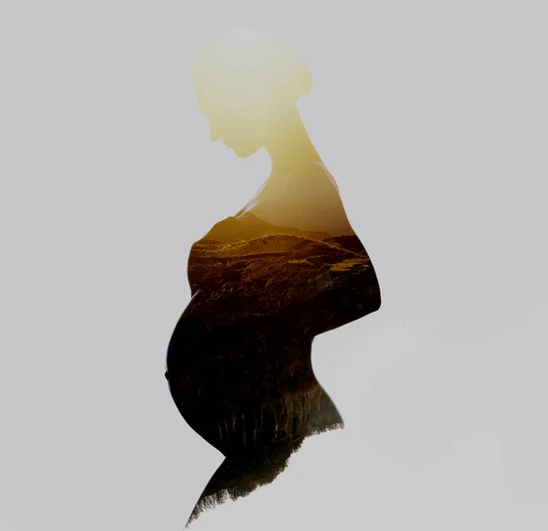 Beautiful silhouette of pregnant woman combined with a mountains — Stock Photo, Image
