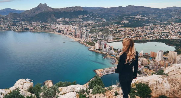 Rear view woman climbed up on peak of Penon de Ifach rock enjoy picturesque view Mediterranean Sea — Stock Photo, Image