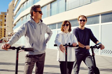 En iyi üç arkadaş 20 'li yaşlarda genç bir kız ve 30' lu yaşlarda erkekler dışarıda elektrikli scooterla geziyorlar.