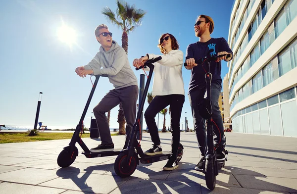 Drei beste Freundinnen junge 20er-30er Mädchen und Jungs verbringen Zeit im Freien versammelt Fahren auf Elektroroller — Stockfoto